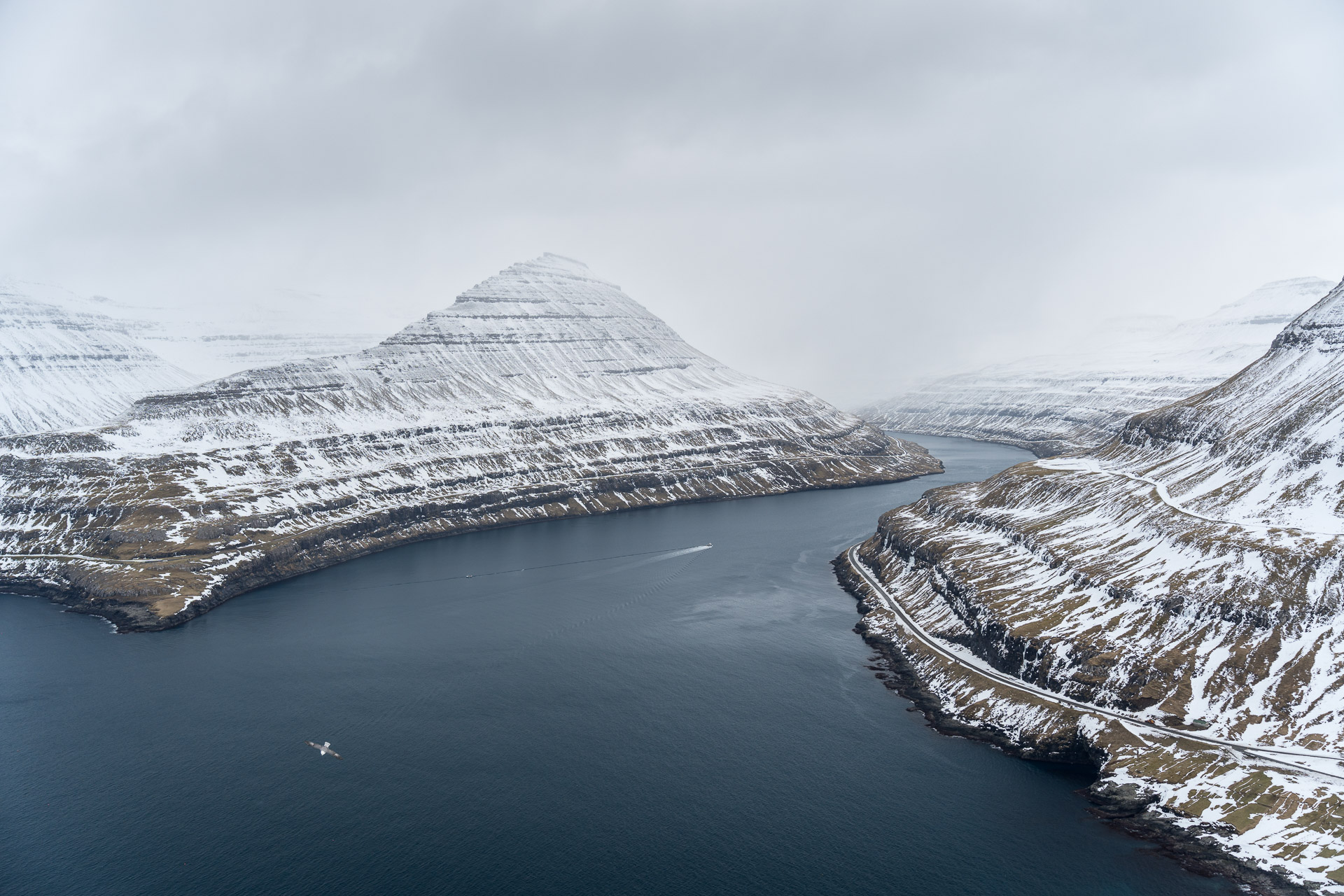 Blick über den Fjord mit verschneiten Bergen